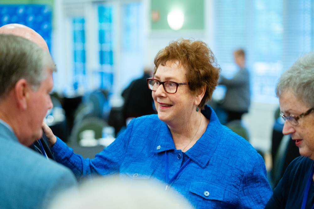 An alumna listens to a fellow alumni, while standing in a circle at the Reunion Dinner.